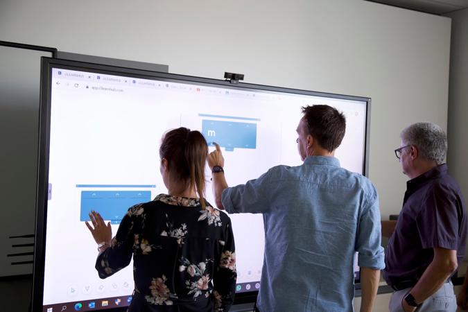 Three adults completing a microlearning module prepared in i3LEARNHUB on an interactive whiteboard.