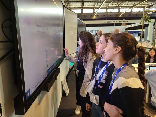 Schoolchildren using i3TOUCH interactive display at an educational fair.