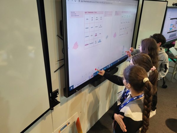 Four schoolchildren using interactive touch display.