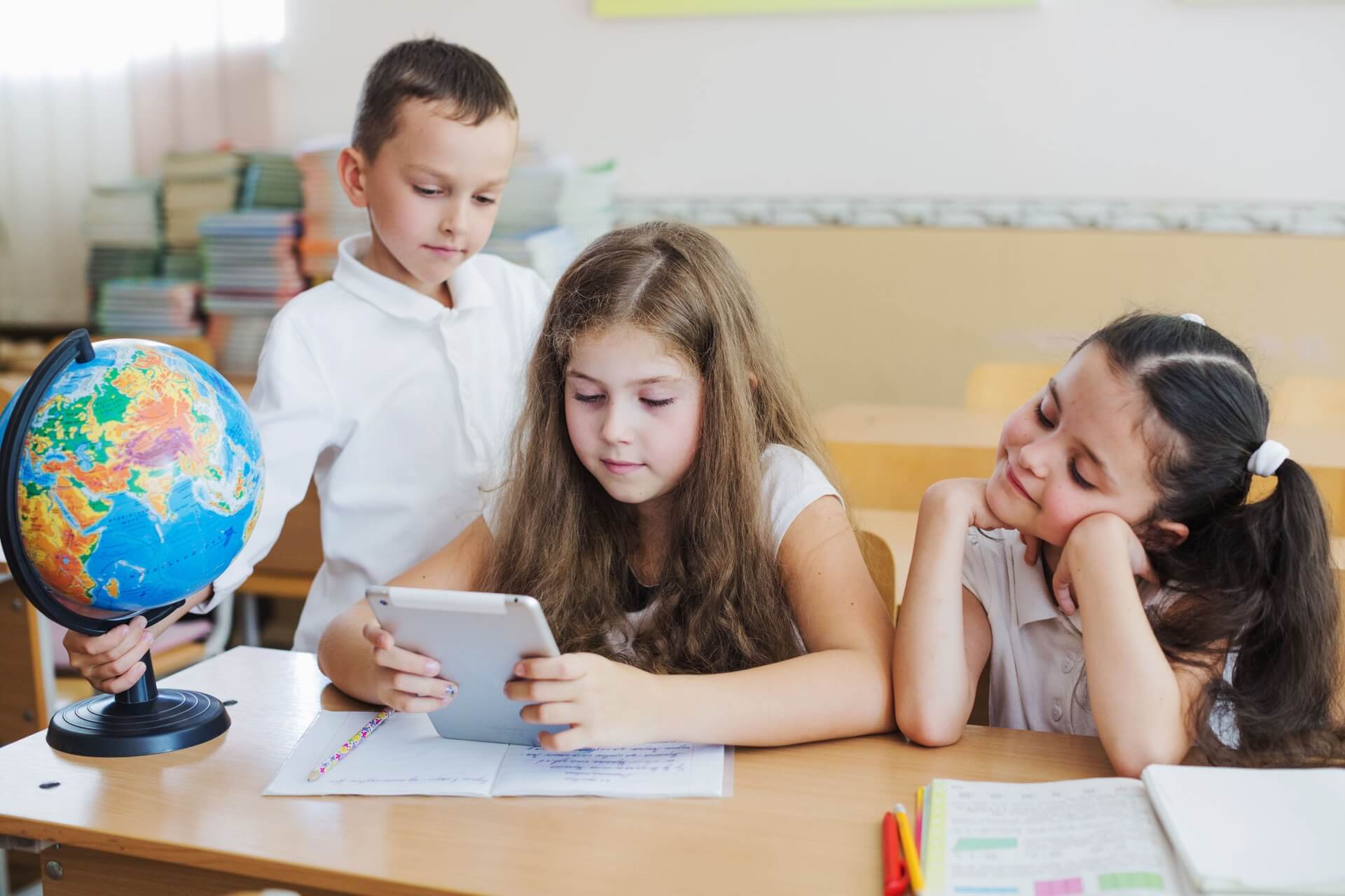 Three students looking at a tablet in the classroom.