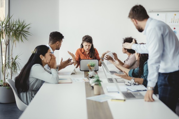 An upset woman staring at a laptop during a business meeting.