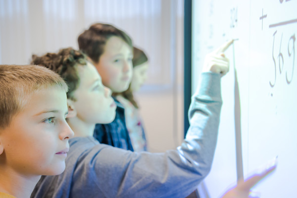 Vier kinderen doen wat wiskundewerk op een interactief whiteboard.